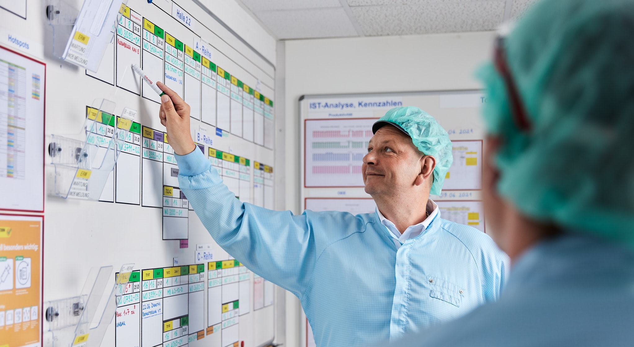 Eine Person in Schutzkleidung zeigt die kurzfristige Lean-Planung einer Produktion. Durch die Weiterbildung an der Swissmem Academy ist die Person bestens auf diese Aufgabe vorbereitet. 